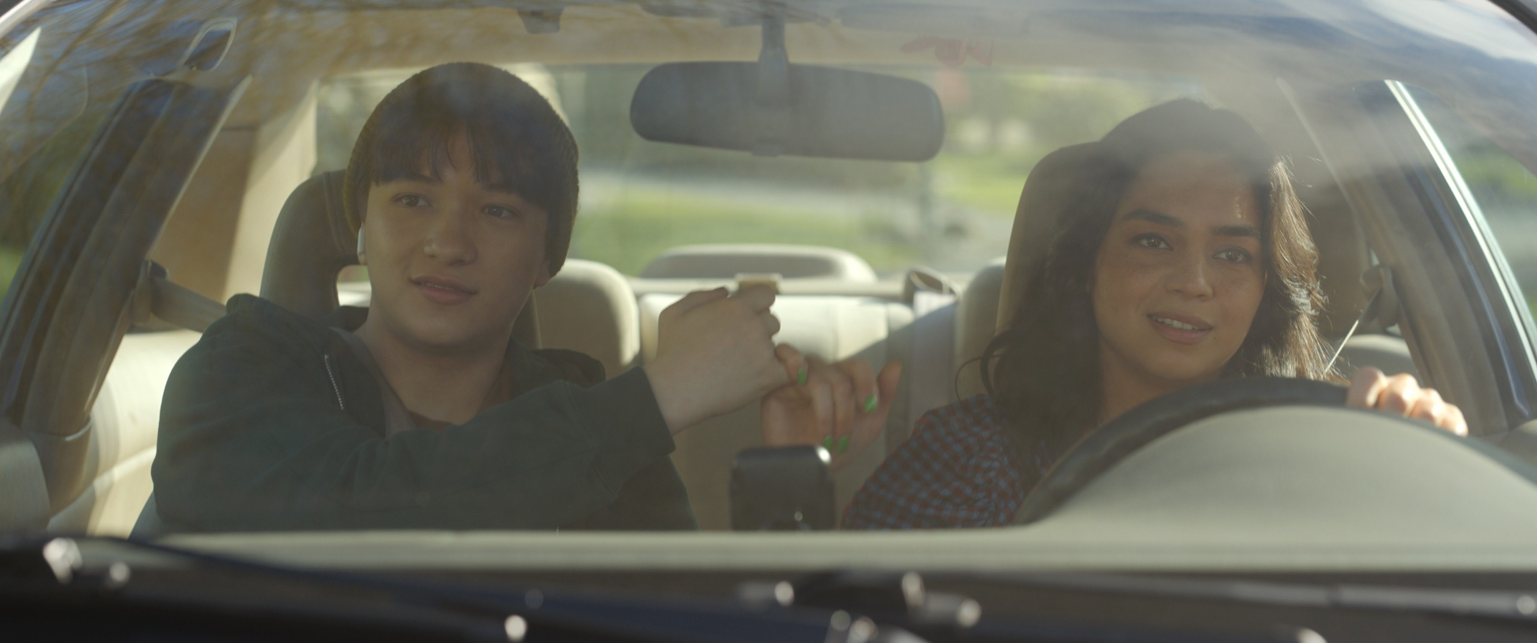Two people in a car are sharing a fist bump, suggesting camaraderie or agreement