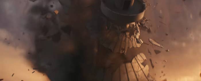 A tower dramatically crumbles amidst flying debris, conveying a sense of chaos and destruction