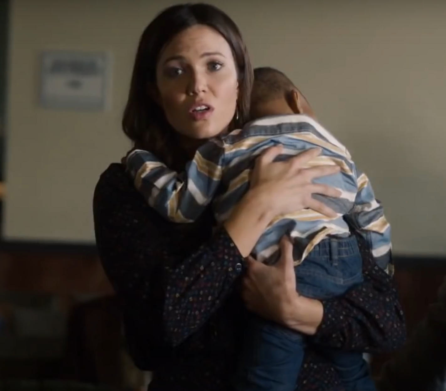 A person holds a child gently in a cozy setting, showing a caring moment