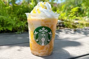 スターバックスのフラペチーノドリンクが屋外の木製テーブルに置かれている。上にはホイップクリームとシロップが乗っている。