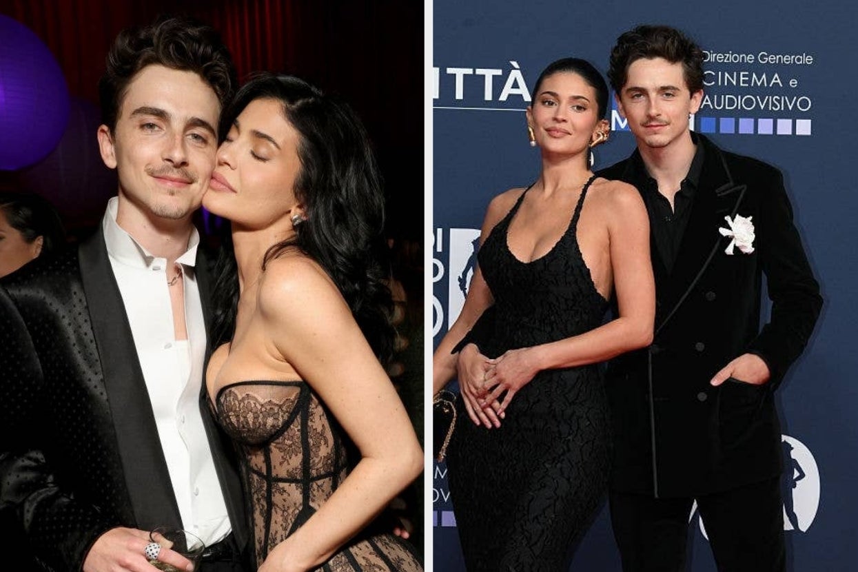 Two celebrities pose on the red carpet. The man is in a tuxedo, and the woman wears a form-fitting, elegant dress with a lace design