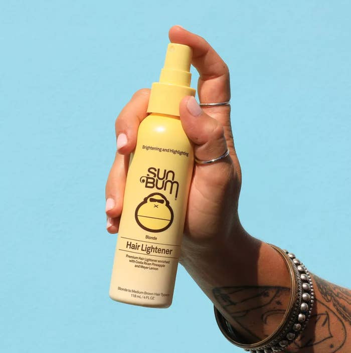 Tangan memegang sebotol Lightener Rambut Pirang Sun