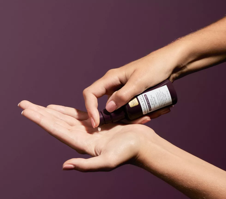Model menerapkan sejumlah kecil serum rambut ke telapak tangan terbuka