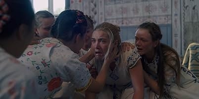 A group of women comfort one woman who appears distressed in a room with Scandinavian-style decor