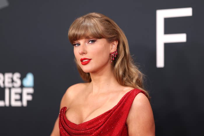 Person in elegant, off-shoulder gown, styled hair, and statement earrings attends a red carpet event