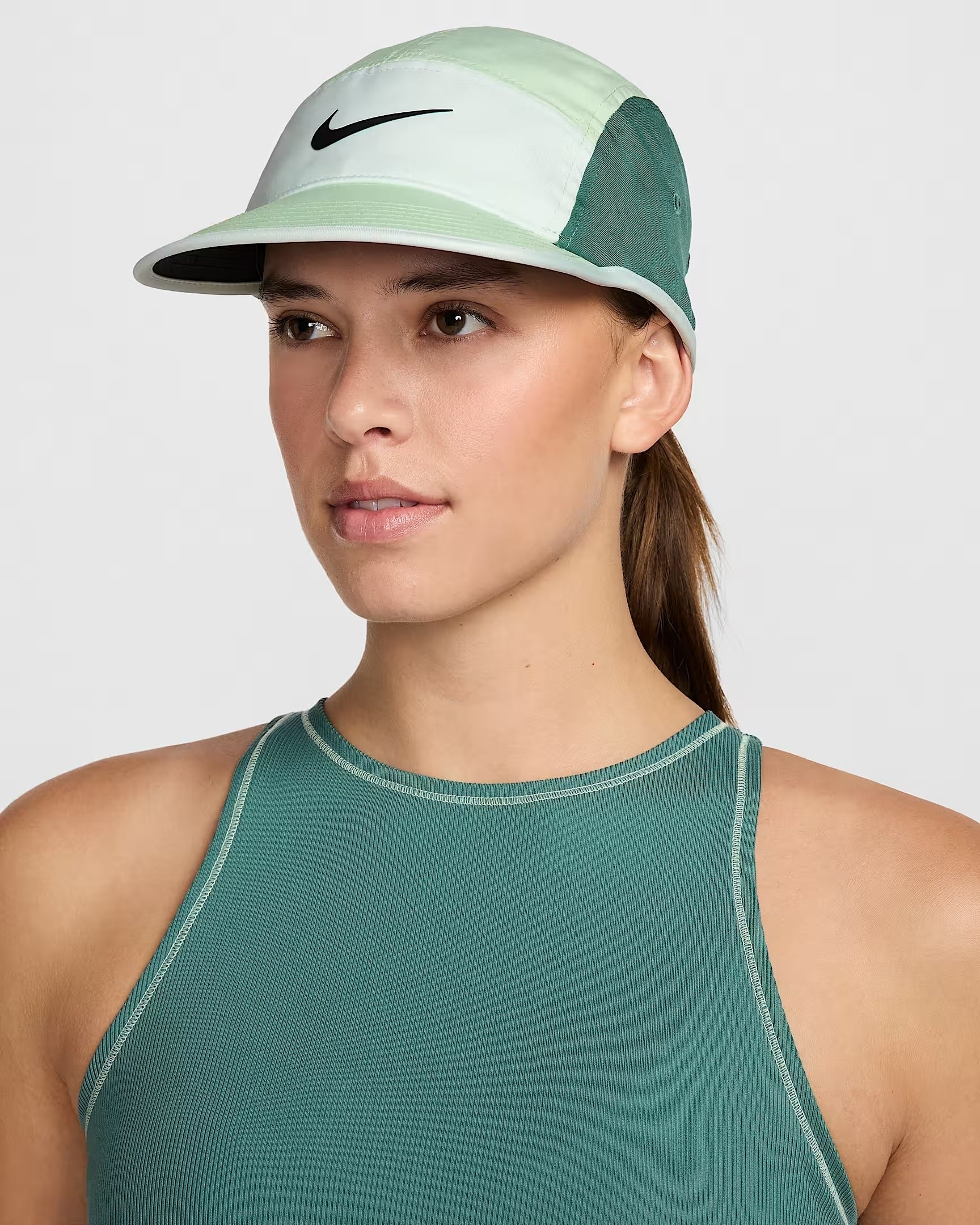Orang yang mengenakan top atletik tanpa lengan dan topi olahraga dengan logo yang berbeda, cocok untuk berbelanja pakaian aktif