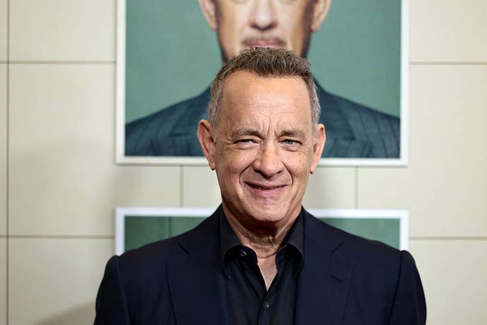 Man in a dark suit smiling in front of a backdrop with his portrait