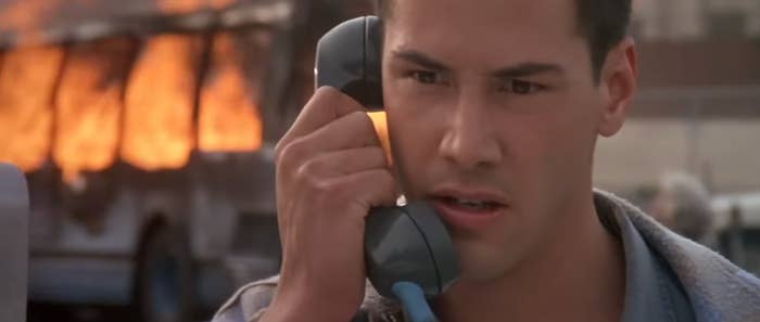 A idiosyncratic holding a telephone appears tense, with a burning conveyance successful the background, suggesting an urgent situation