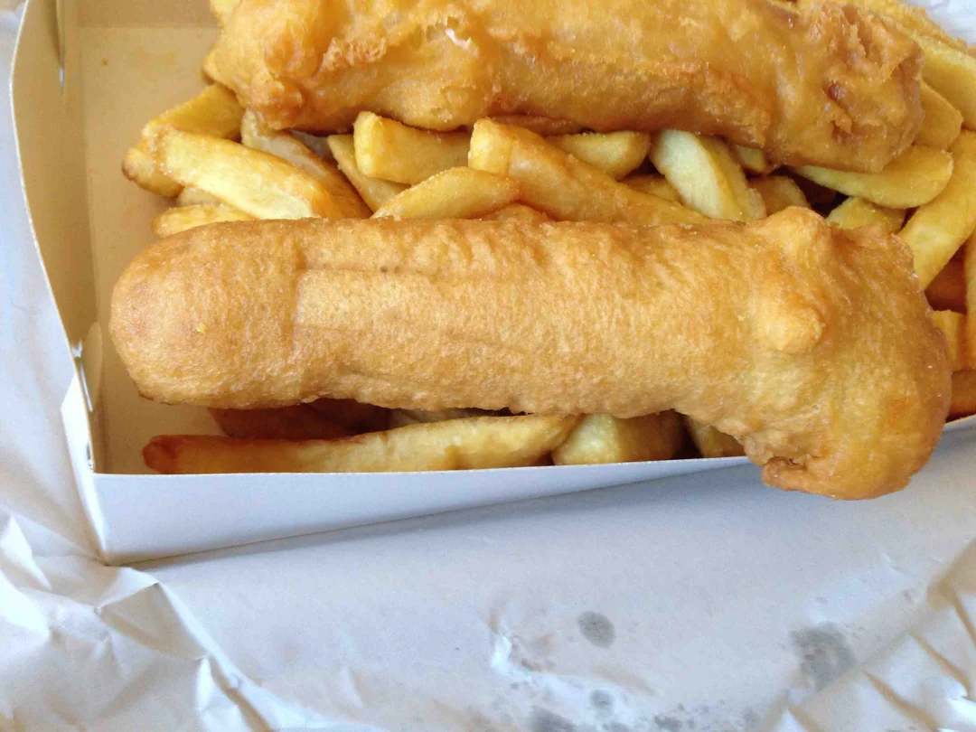 Box of battered fish and chips, presented on white paper