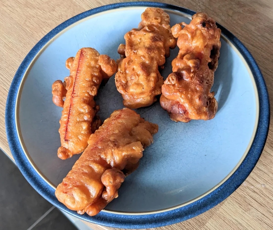 Four deep-fried KitKat bars on a blue plate rest on a wooden surface