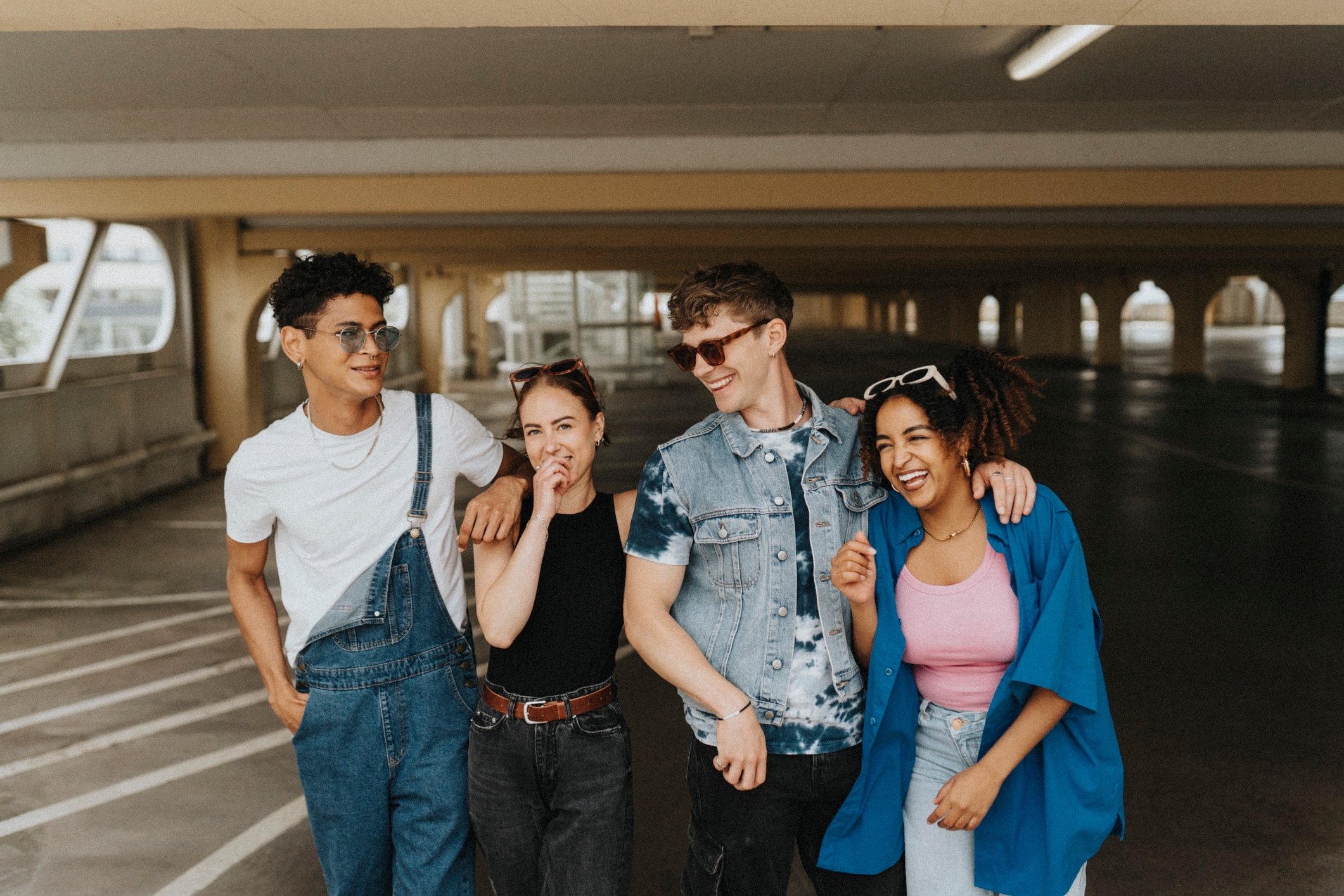 Fire venner i tilfeldige antrekk ler og går sammen i et parkeringshus