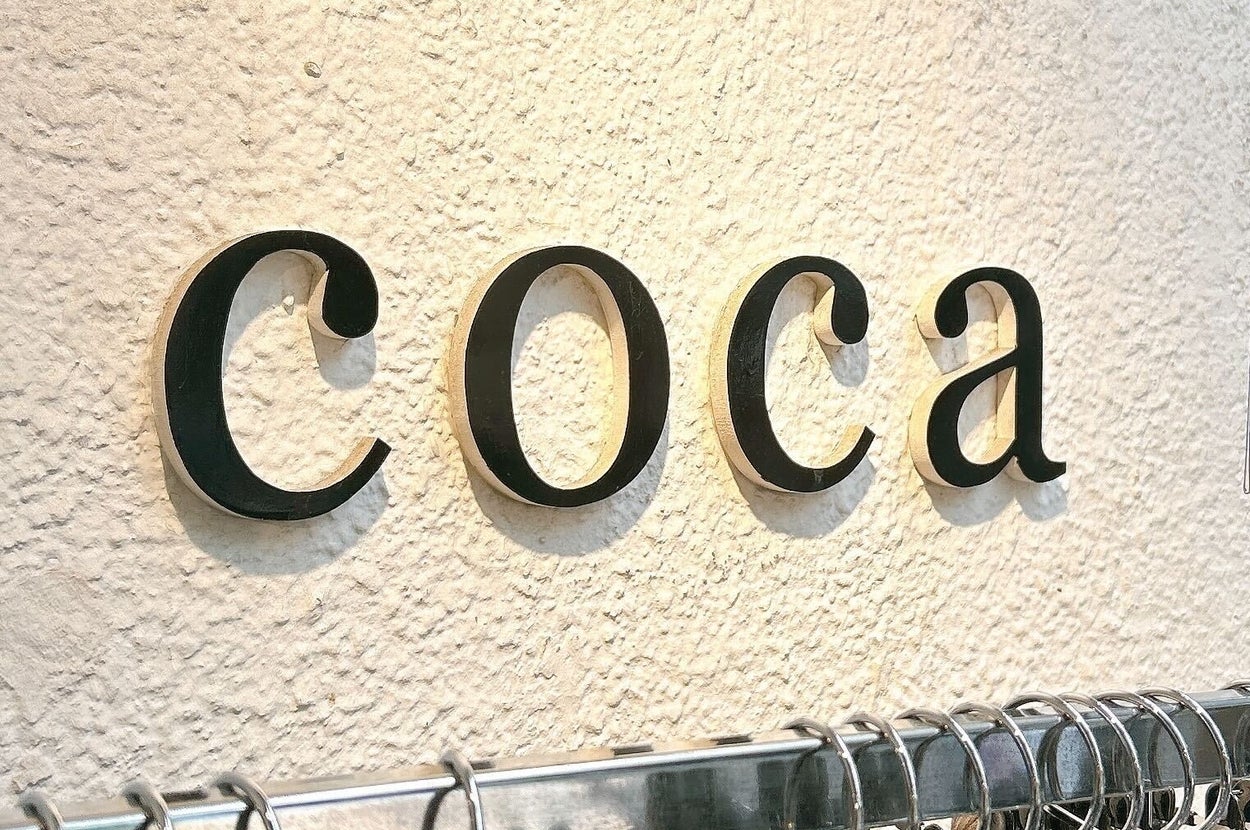 壁に取り付けられた「coca」のサインと洋服ラック。