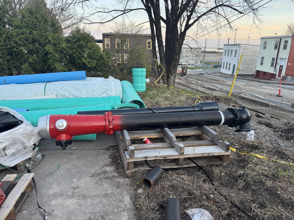 Large industrial pipes and equipment on pallets at an outdoor construction site
