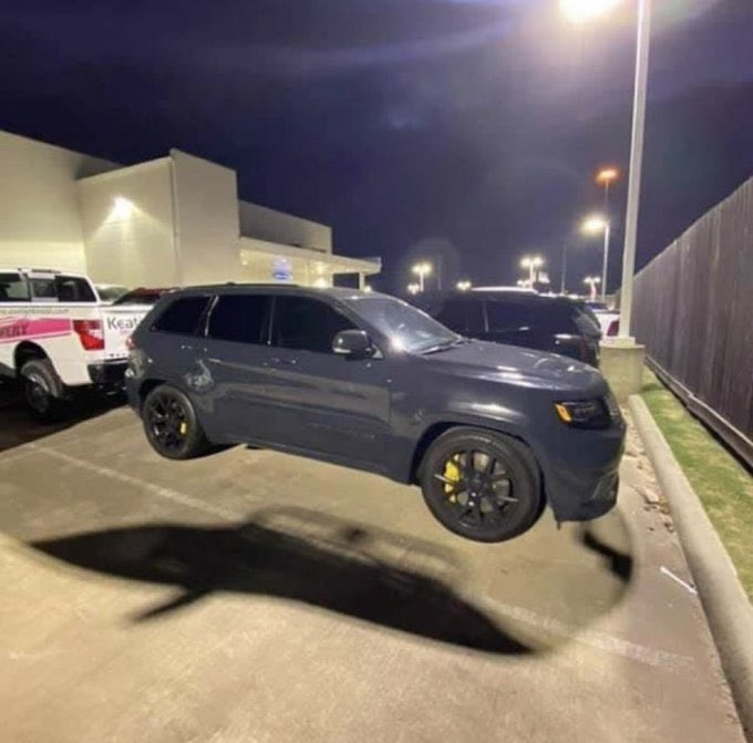 Black SUV with yellow brake calipers parked in a lot at night, under streetlights
