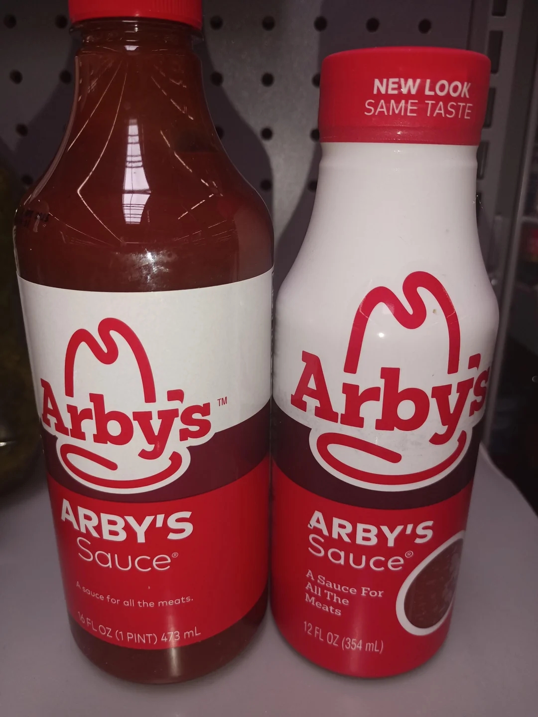 Two bottles of Arby&#x27;s Sauce on a shelf, showcasing different label designs with the text &quot;New Look, Same Taste.&quot;