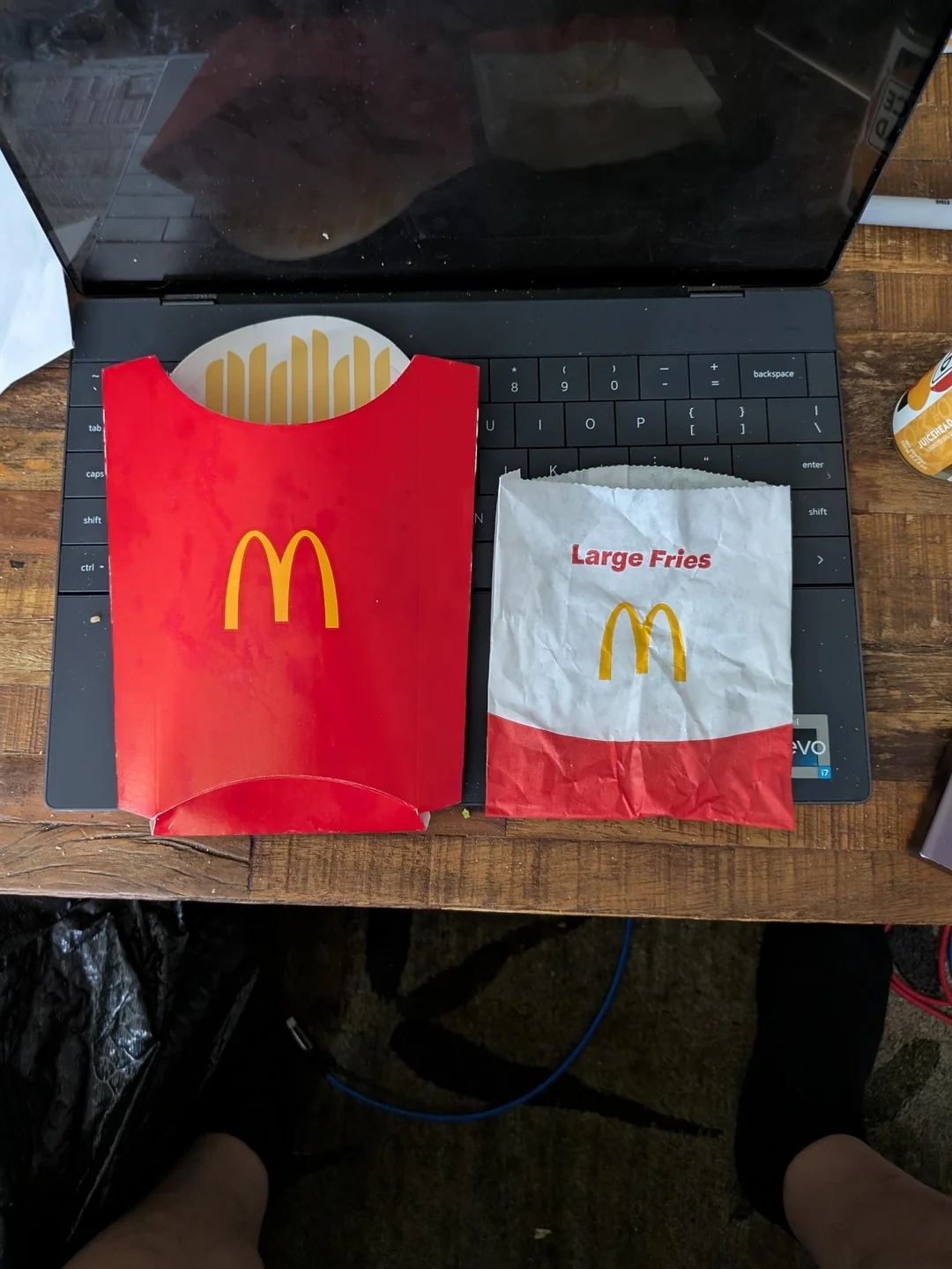 Empty McDonald&#x27;s fry carton and bag labeled &quot;Large Fries&quot; on a laptop