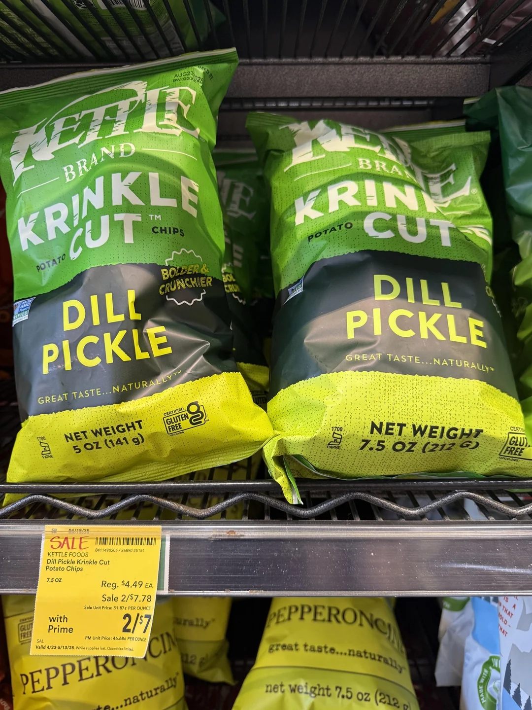 Bags of Kettle Brand Krinkle Cut Dill Pickle chips on a store shelf with a sale sign offering two bags for $7
