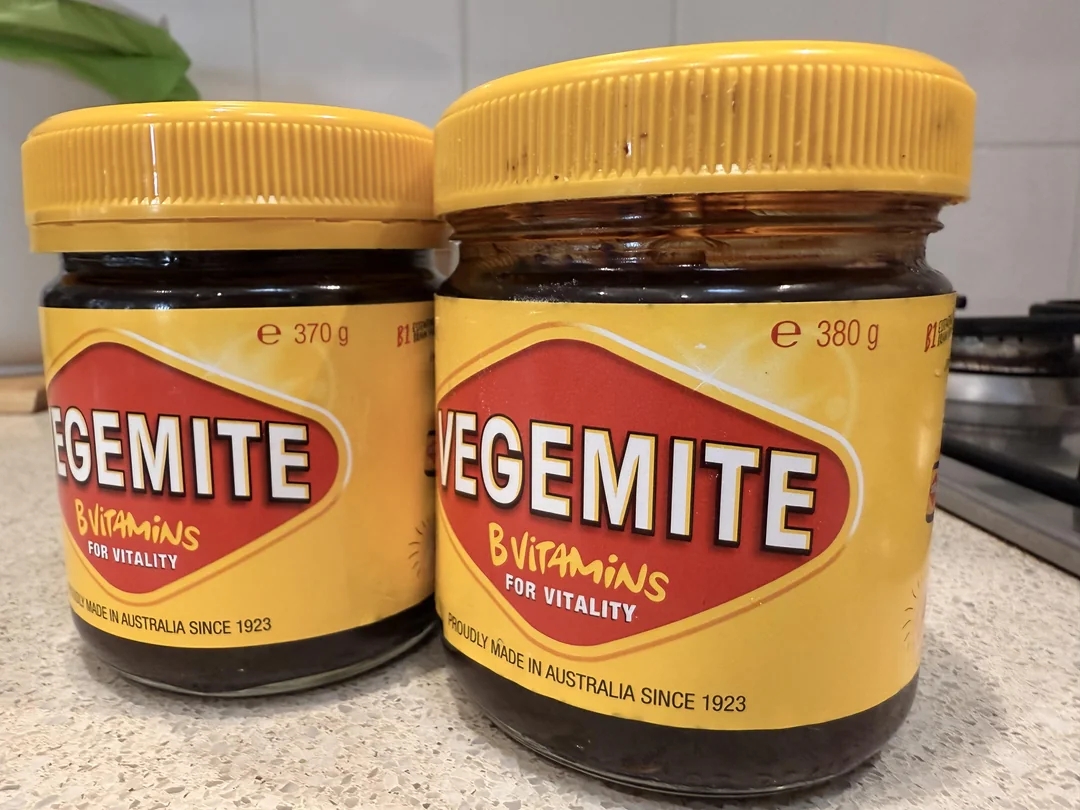 Two jars of Vegemite are on a kitchen counter, highlighting the spread&#x27;s branding and nutritional claim of &quot;B Vitamins for vitality.&quot;