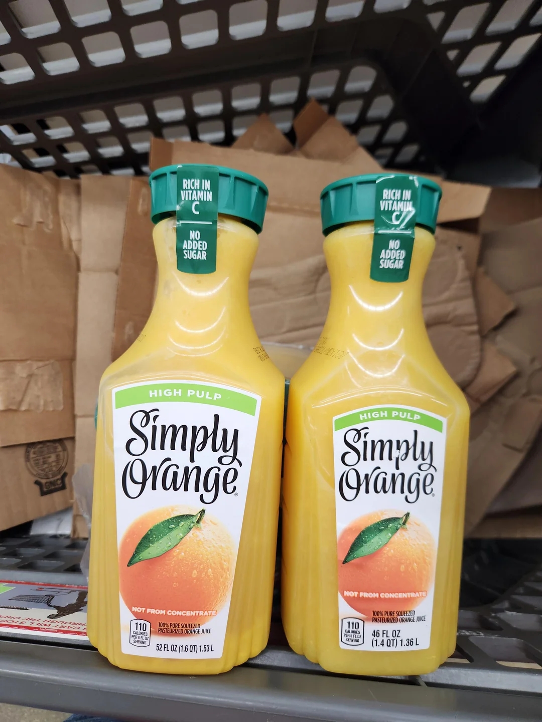 Two bottles of Simply Orange High Pulp orange juice on a store shelf, labeled &quot;Rich in Vitamin C&quot; and &quot;No Added Sugar.&quot;