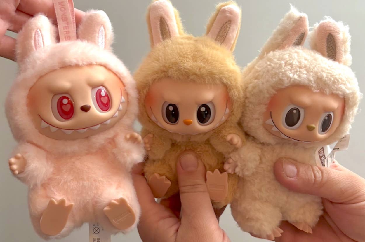 Three plush toys with cute, fierce faces and bunny ears are held in hands. Each toy has distinct facial expressions