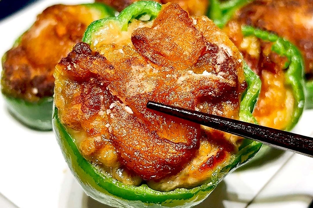 肉詰めピーマンが盛られた皿。上にはジューシーな肉とカリカリの外皮。箸が肉を持ち上げる。
