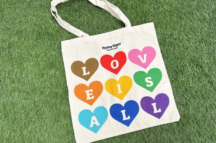 草の上に置かれたトートバッグ。ハート型の中に「LOVE IS ALL」の文字が書かれている。