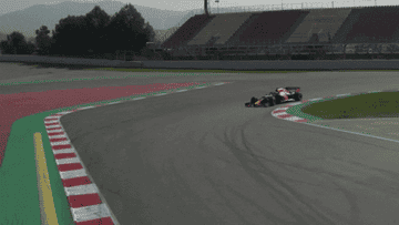 Race car speeding around a track curve during a daytime event, showcasing precision driving and competitive motorsport