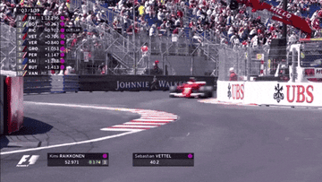 Formula 1 car speeds around a track corner during a race, with a leaderboard displayed. Crowd watches from the stands