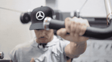 Person in a cap using gym equipment, focusing on a chest press exercise