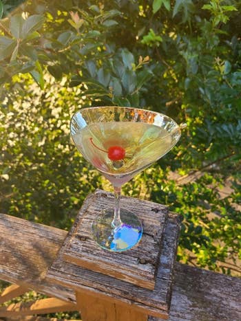 A cocktail solid with a cherry sits connected a woody railing, surrounded by lush greenery successful the background