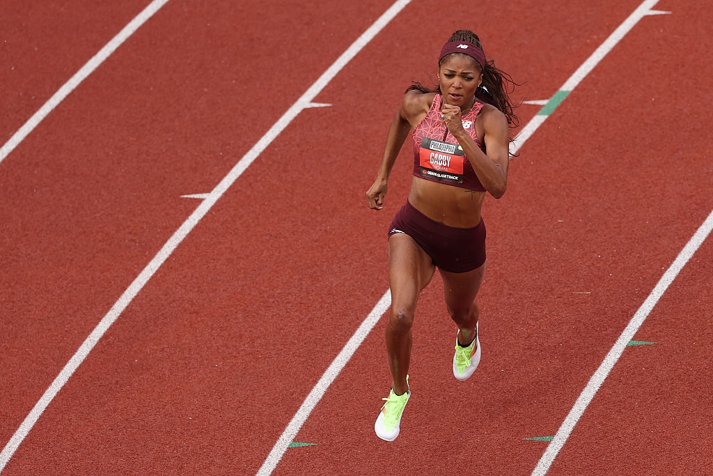 Athlete in running gear mid-stride on a track during a race, focused on competition