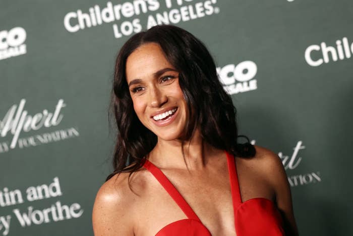 A woman smiling at a formal event, wearing a sleeveless gown