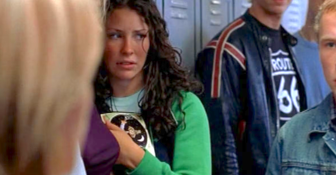 A concerned woman holding a notebook in a school hallway, standing among other students