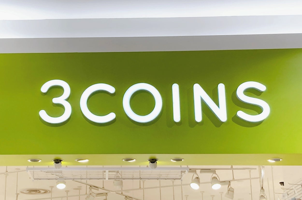 3COINSストアの店頭。LEDライトのロゴサインが目立つ。店内に商品が並ぶ。