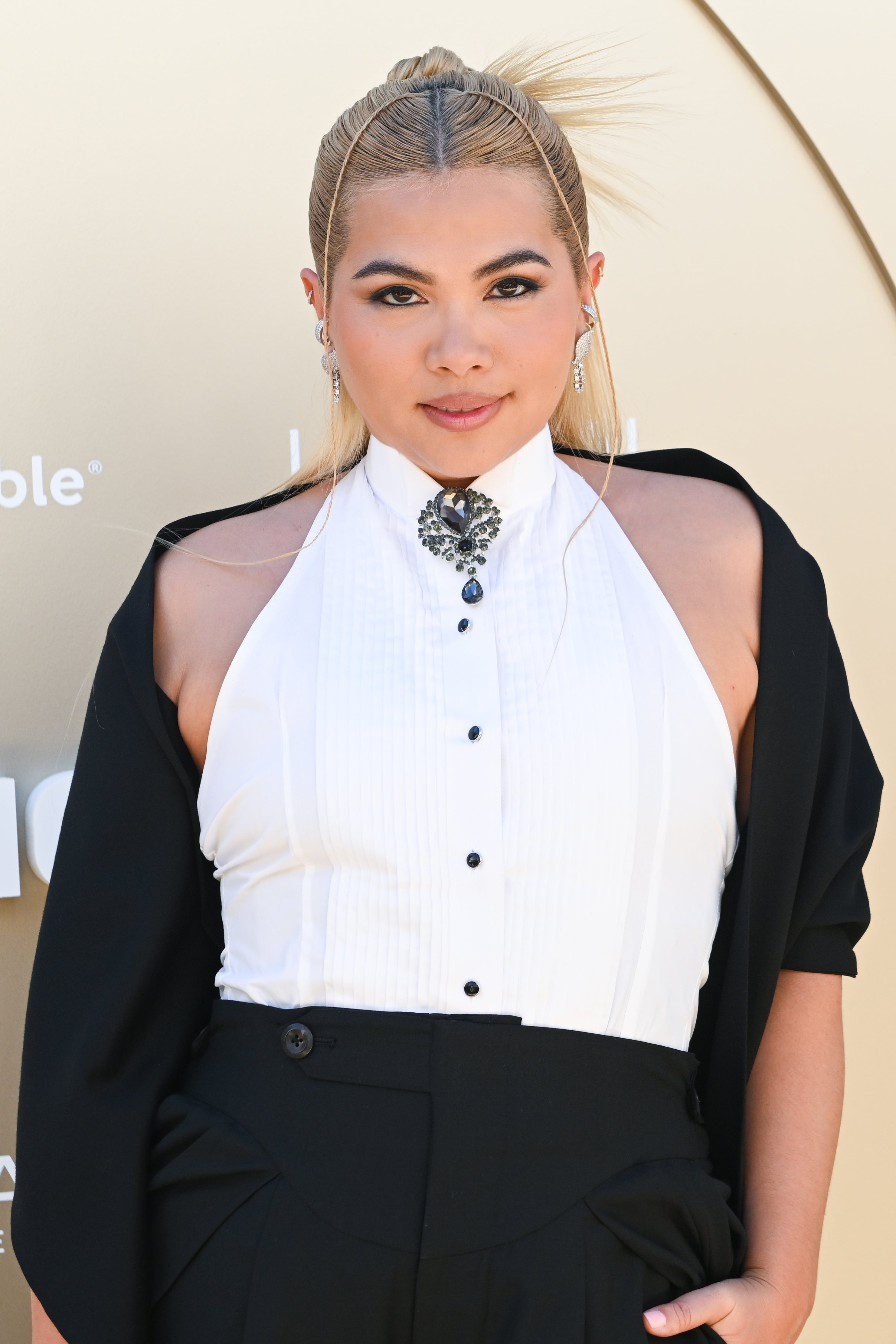 Person in formal black and white outfit with statement necklace, outside on a carpet event, stylish hair updo