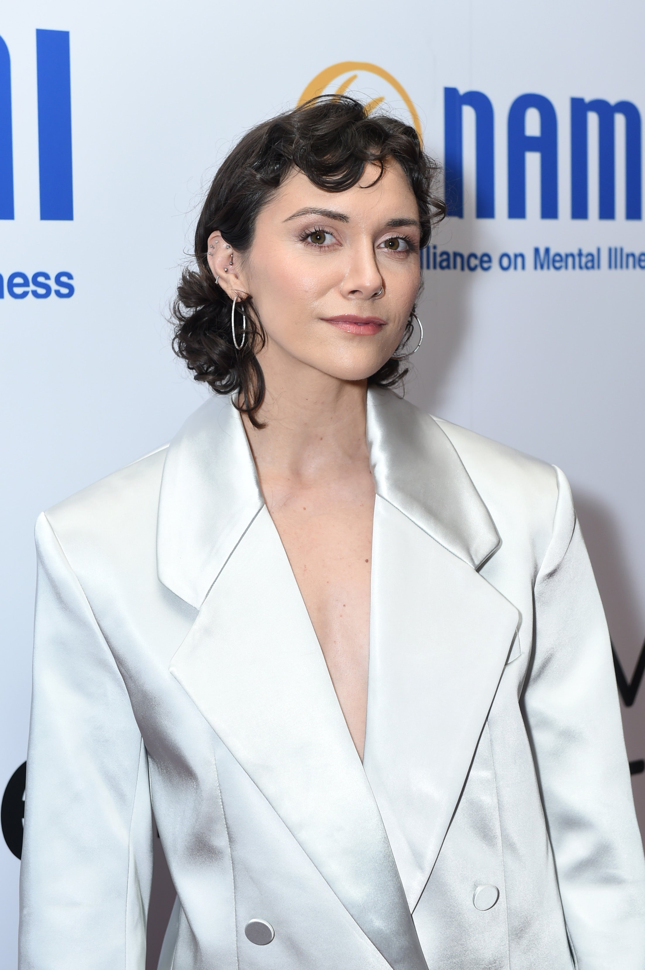 Person in a sleek, satin-like blazer with prominent lapels poses confidently at a mental health event