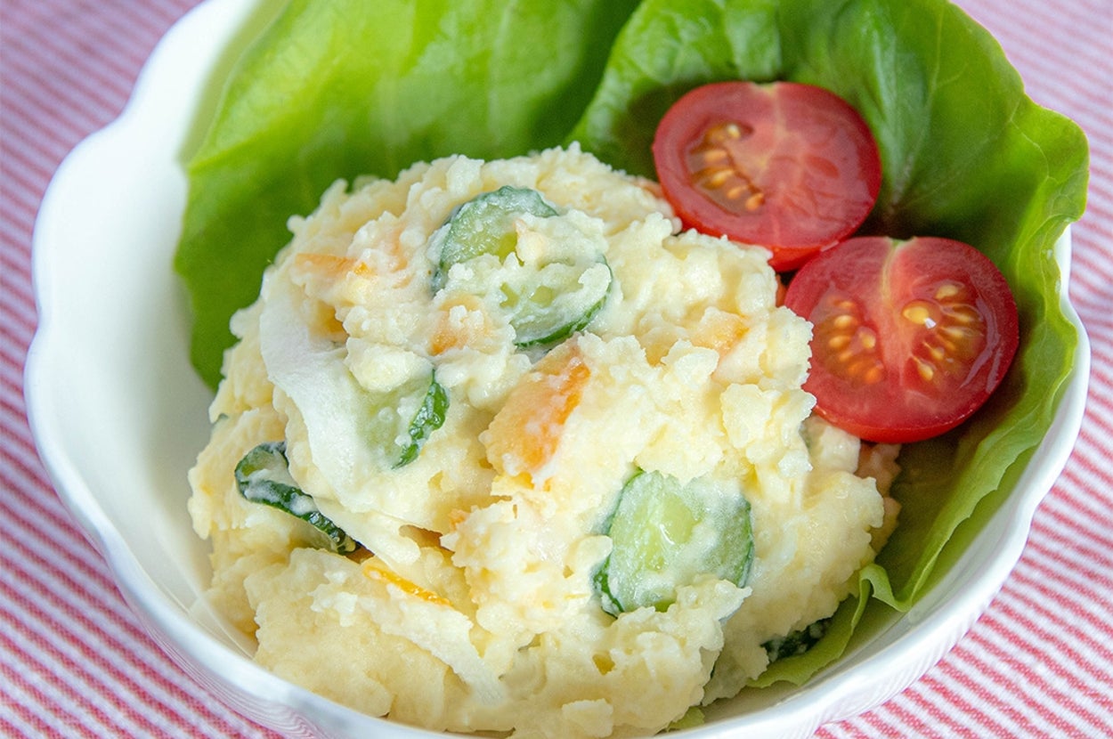 レタスとトマトが添えられたポテトサラダが白い器に盛られている。