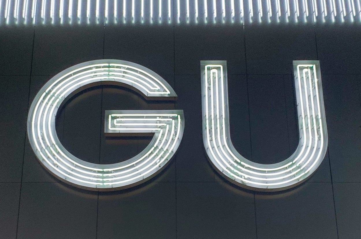 GUのネオンサインが閉店後の店舗前に輝いている。
