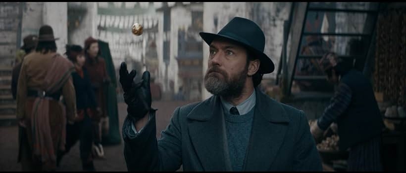 A person in a vintage detective outfit with a hat and gloves is tossing a small object in a historic-looking street setting