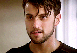 Person with wet hair and a short beard gazing intently, wearing a casual black T-shirt