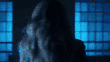 Person with long hair dances energetically in a dimly lit room