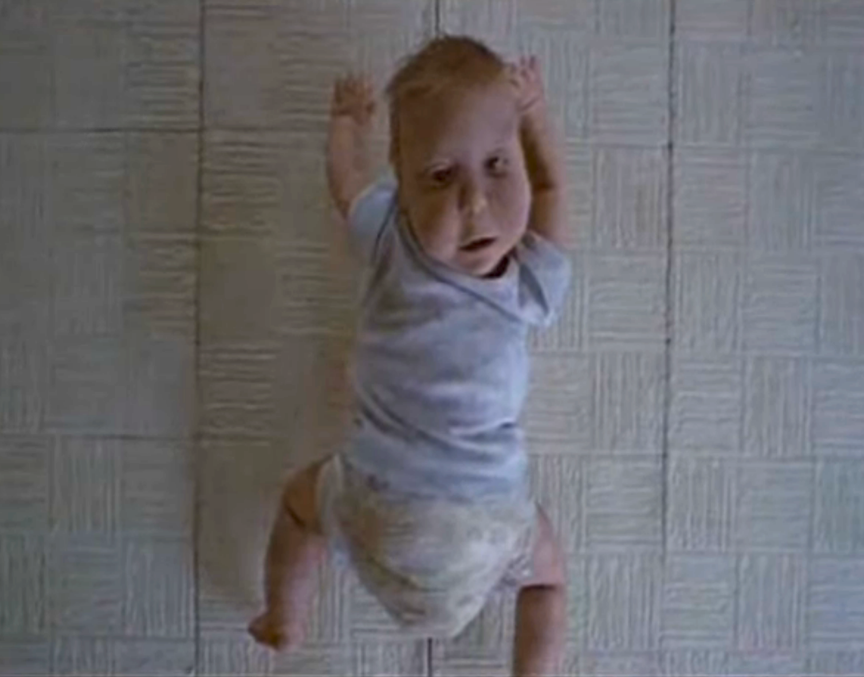Creepy fake baby crawling on ceiling with its head turned around so it faces back down