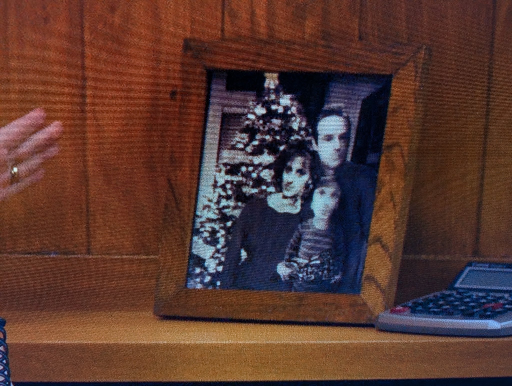 Framed family photo of three people standing in front of a Christmas tree, but the people are badly photoshopped in, especially the child