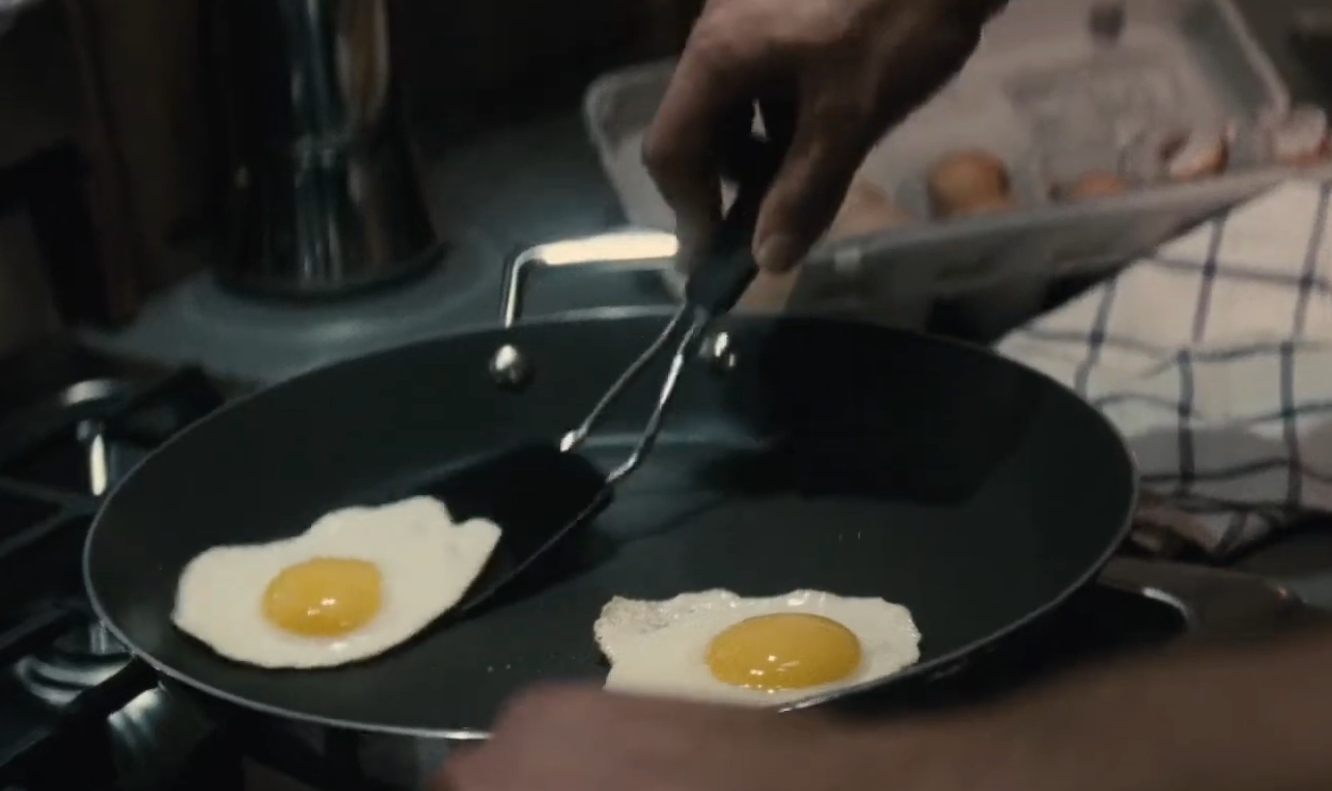 Two fake-looking sunny-side-up eggs cooking in a pan