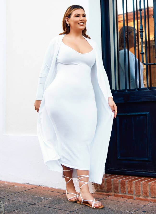 model successful  a sleek, fitted achromatic  formal  and sandals, posing confidently connected  a sidewalk by a building