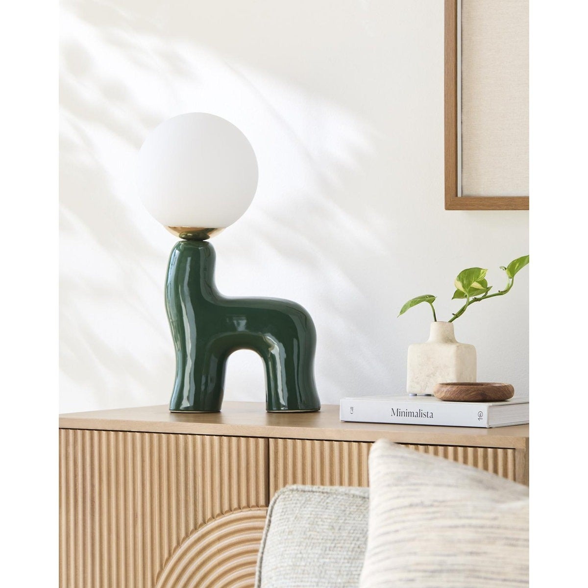 Modern array  lamp with a achromatic  globe connected  a unique, greenish  ceramic basal  connected  a woody  furniture  adjacent  to a minimalist publication  and a tiny  plant