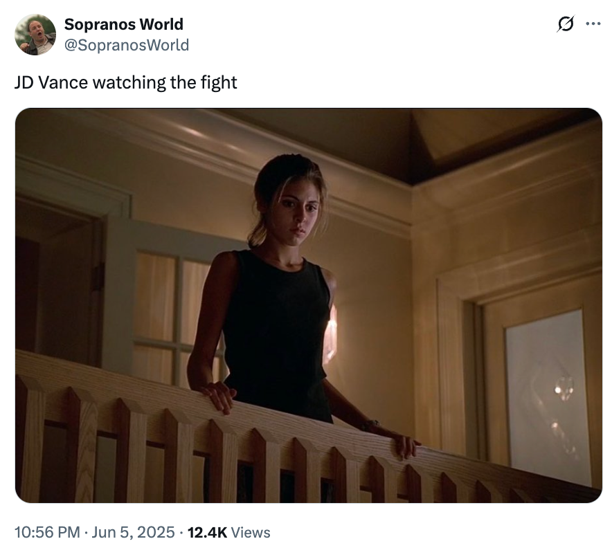 Woman in a black dress stands on a staircase landing, looking down as if watching something below