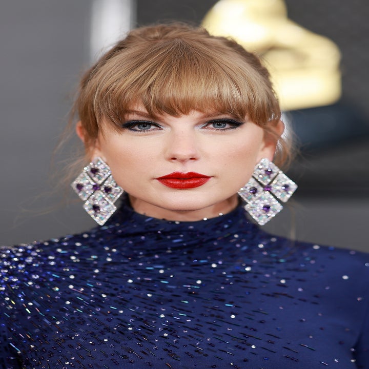 Taylor Swift on the red carpet in a high-neck, sequined gown with large, diamond-shaped earrings