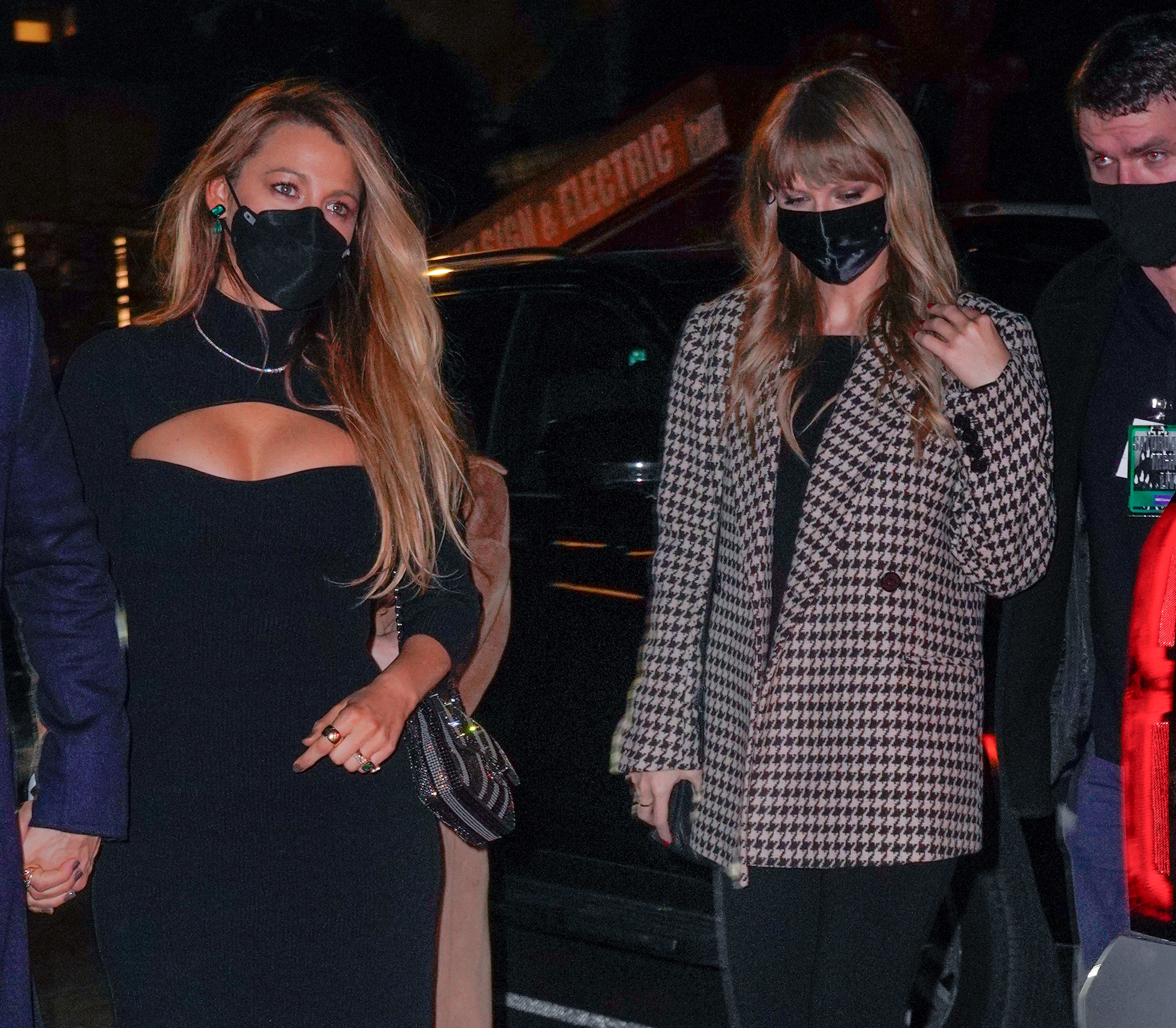 Blake Lively outside in a form-fitting dress while Taylor Swift wears a houndstooth coat, both with masks on