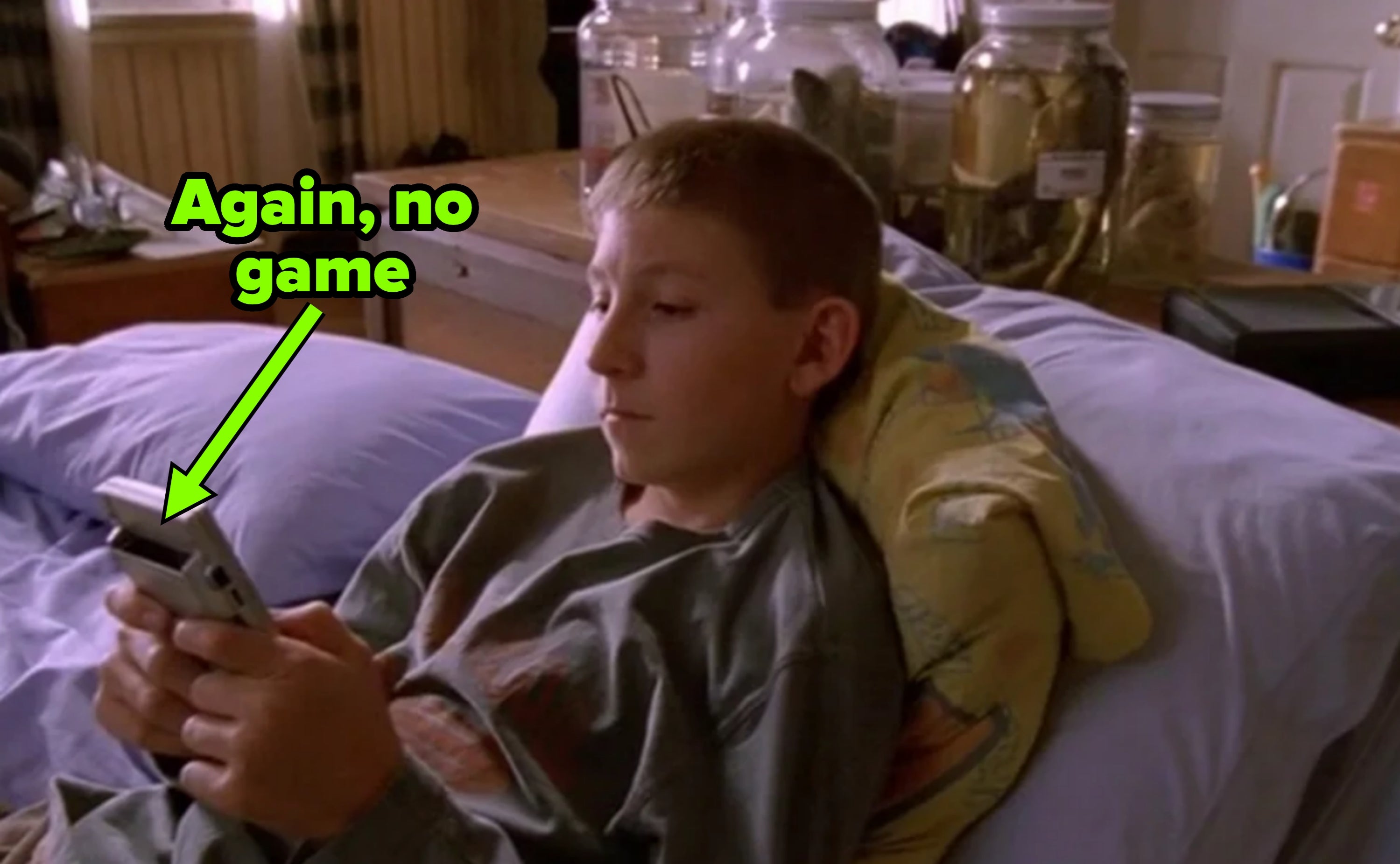 Reese lying on a bed, playing a handheld gaming device, with no game in the cartridge
